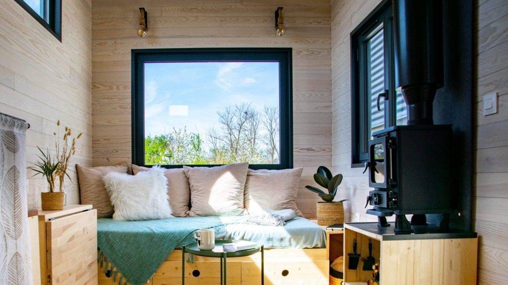 photo intérieure de la tiny house la Odette : vue sur le salon avec canapé et poêle à bois