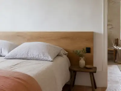 Chambre à coucher avec une tête de lit en bois clair fixée contre un mur blanc