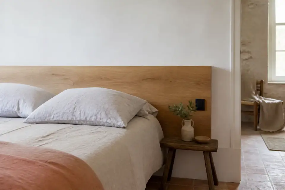 Chambre à coucher avec une tête de lit en bois clair fixée contre un mur blanc
