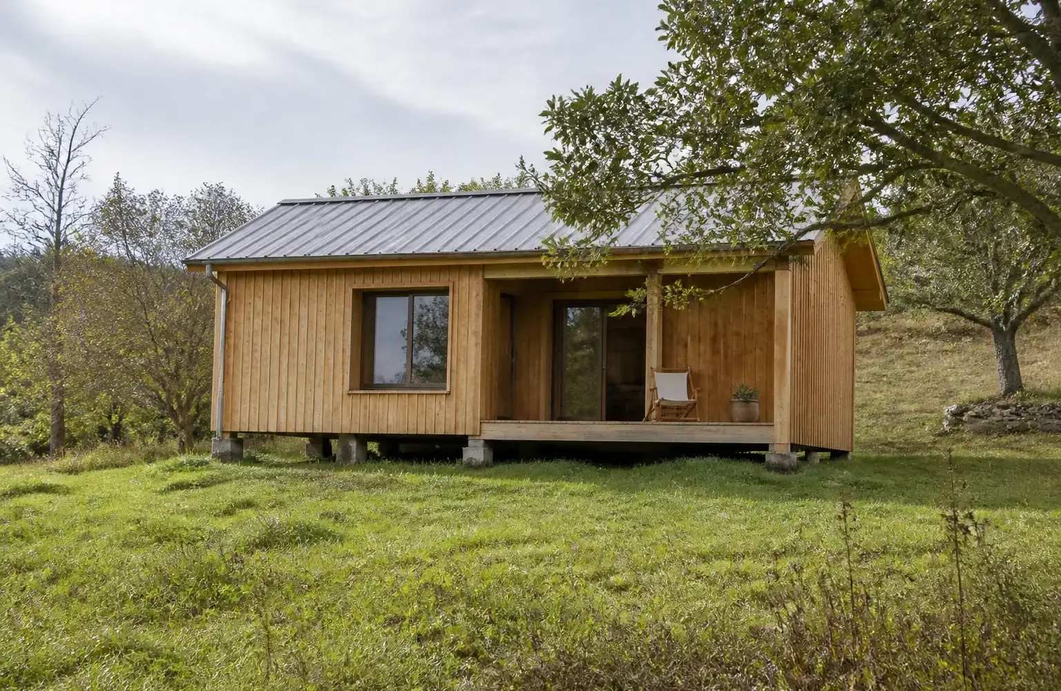 Petite maison en bois posée sur des fondations au milieu d’un terrain dégagé